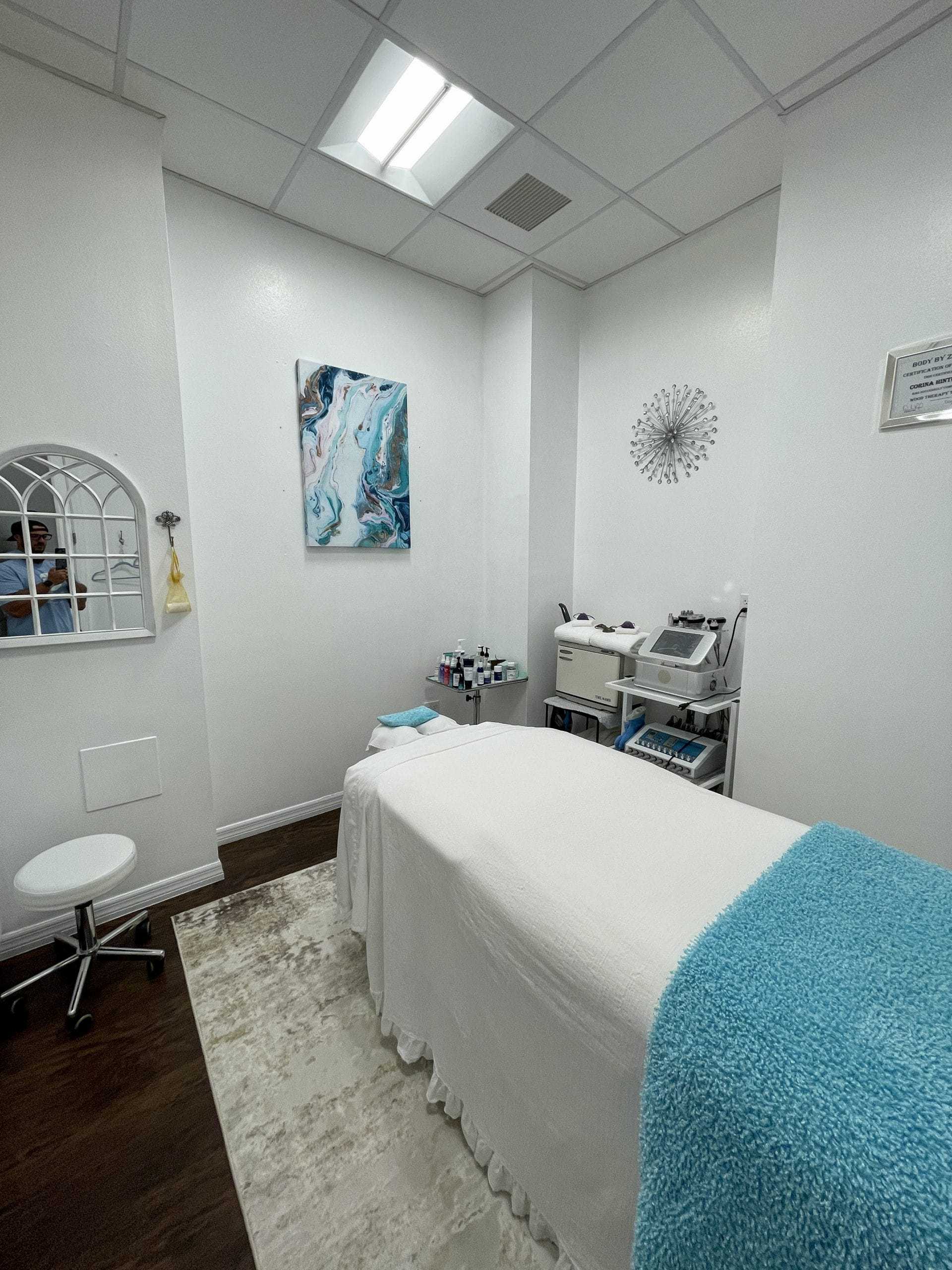 Spa treatment room with a massage table, modern decor, and soothing white and blue accents.