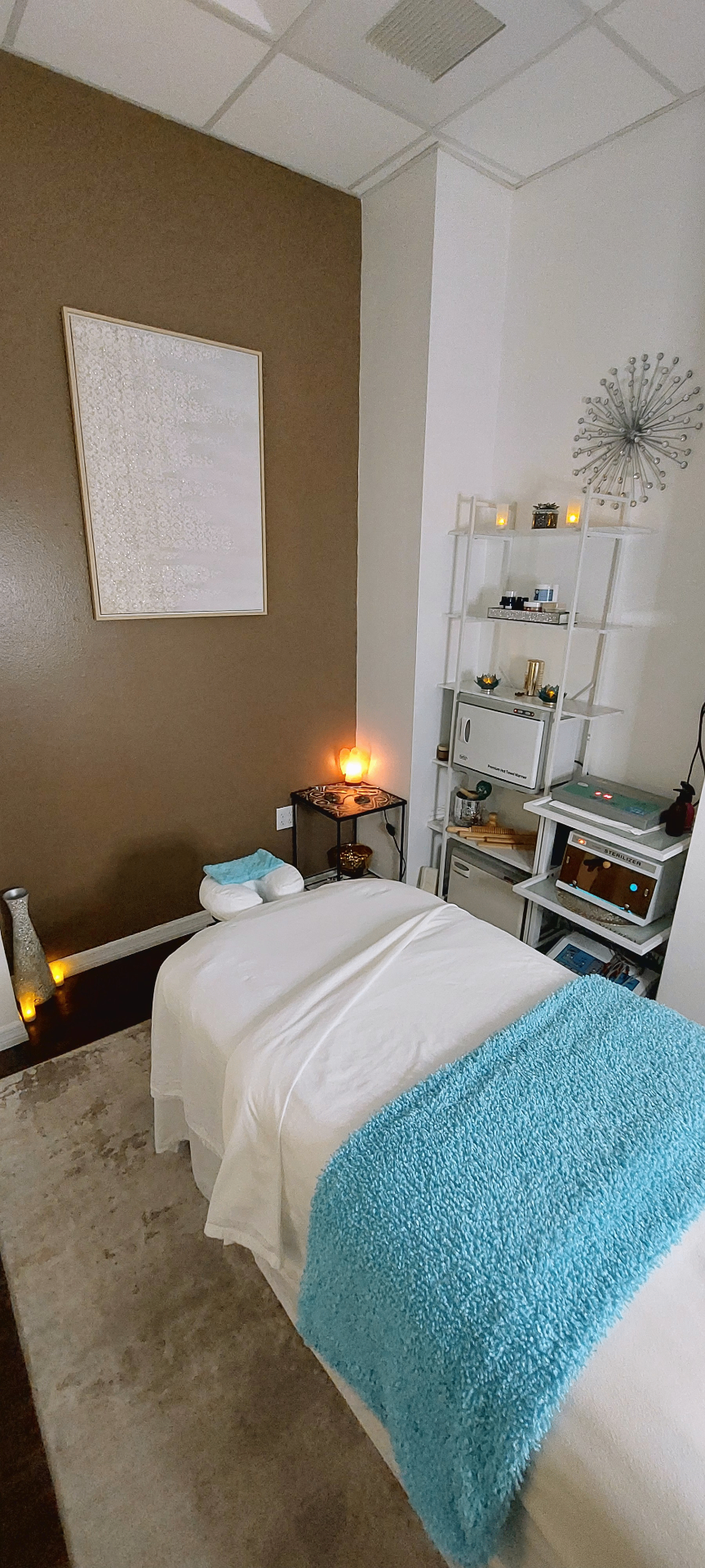Warm treatment room at Body by Corina with candles, framed art, and turquoise accents.